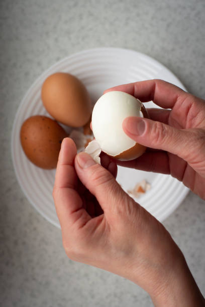 istock Caucasian female peeling hard boiled eggs closeup view from above 1490657813
