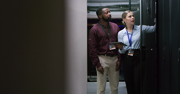 Team, man and woman technician check server room for cloud computing or cyber security at night. Tech, it engineer and people working on database for maintenance or networking in data center