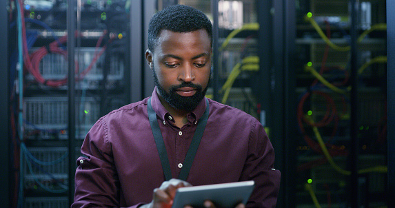 Tablet, man and technician check server room for cloud computing or cyber security at night. Tech, it engineer and male person working on database for maintenance or networking in data center