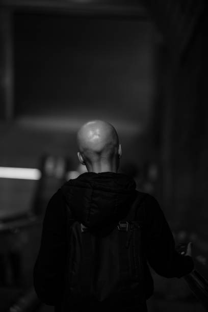 A bald Caucasian male going down the stairs in grayscale