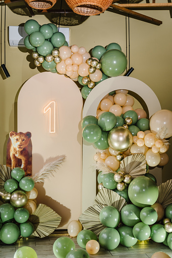 Arch decorated green, brown golden balloons, big paper decor leaves for wedding ceremony. Celebration baptism concept. Trendy autumn decor, photo wall. Copy space for text. Reception at birthday party