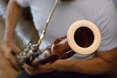 closeup of unrecognizable man playing bassoon at home, focus on bassoon bell ring.