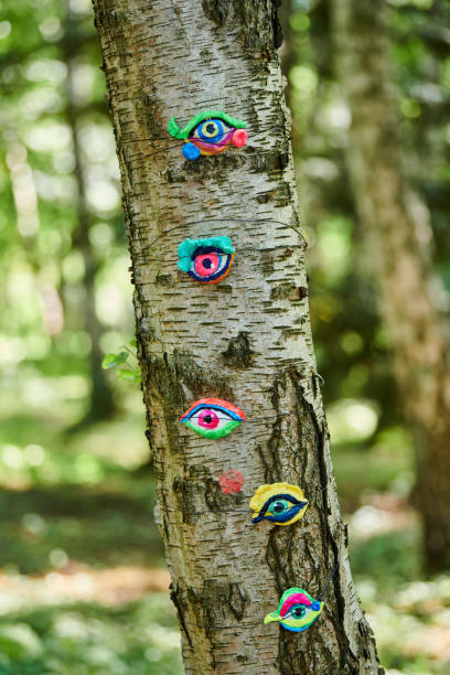 istock Art object of human eyes on tree trunk in green forest background, trees sight feeling ecological concept 1490660239