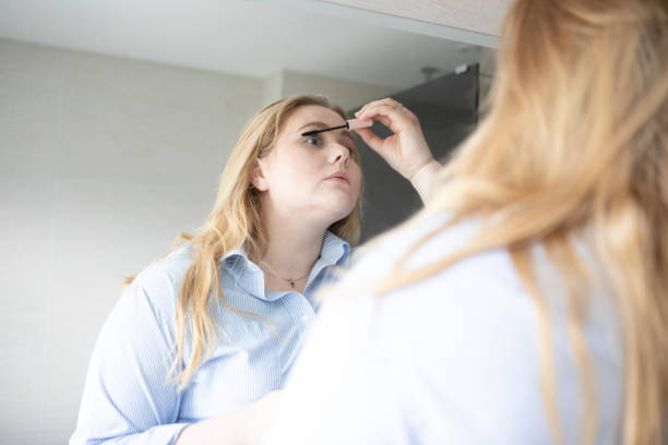 istock Young woman putting on make-up in front of a mirror 1490660447