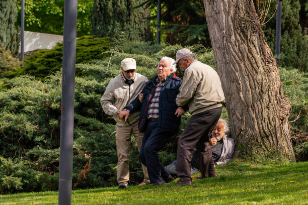 istock Active Senior Old Friends Having A Nice Day At  Park. 
Friends help old man with backache while getting up. 1490660670