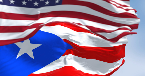 Flag of Puerto Rico waving with the United States flag on a clear day. Puerto Rico is a Caribbean island and unincorporated territory of the United States. 3D illustration render. Selective focus