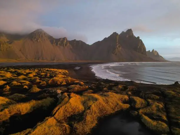 Photo of Scenic view of a beach with lush green grass and distant mountain Vestrahorn, Iceland
