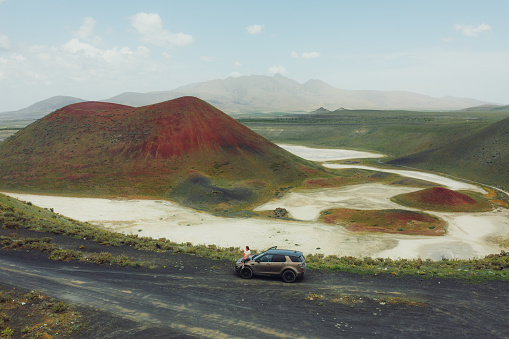 4x4 car parked on dirt road among the mountain and meadow on sunny day in summer at Iceland