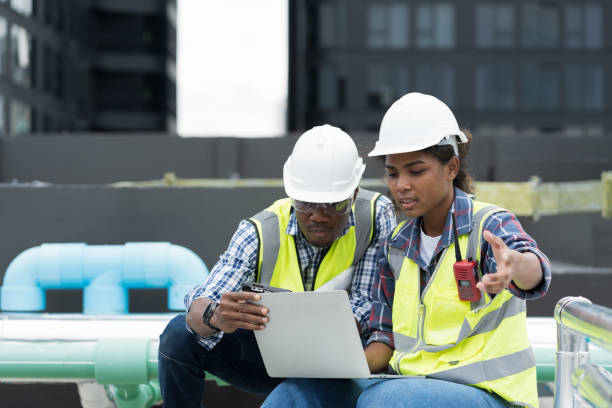 istock Male and female engineer worker working with laptop computer discuss and inspecting structure of building at rooftop of building at construction site 1490662973