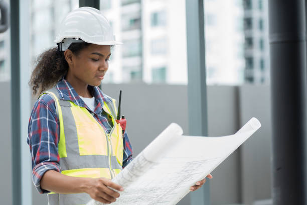 istock Female engineer worker working, holding blueprint and inspecting structure of building at rooftop of building at construction site 1490663008