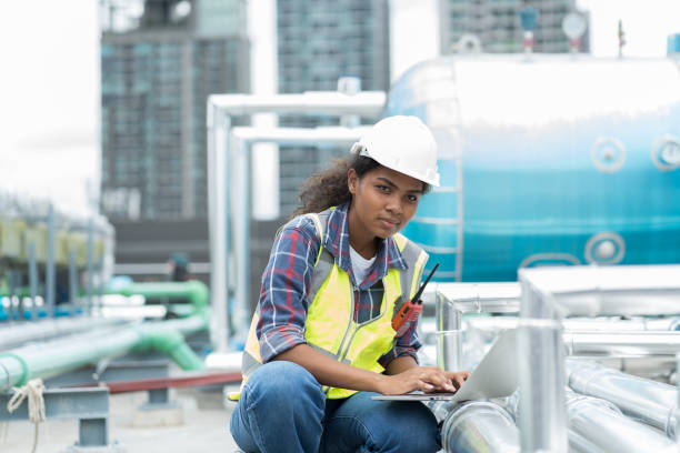 istock Female engineer worker using laptop computer inspecting quality sewer pipes at rooftop of building. African American woman engineer working, checking or maintenance sewer pipes at construction site 1490663009