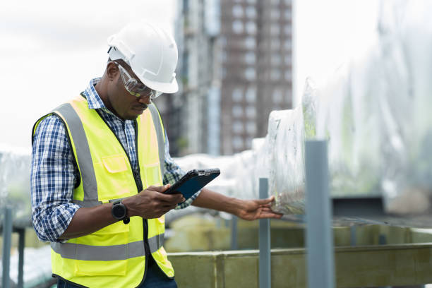 istock Male engineer worker working with digital tablet inspecting quality ventilation, air conditioning at rooftop of building. Male technician maintenance pipe system for ventilation at construction site 1490663034