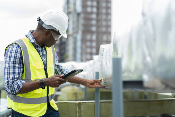 istock Male engineer worker working with digital tablet inspecting quality ventilation, air conditioning at rooftop of building. Male technician maintenance pipe system for ventilation at construction site 1490663040