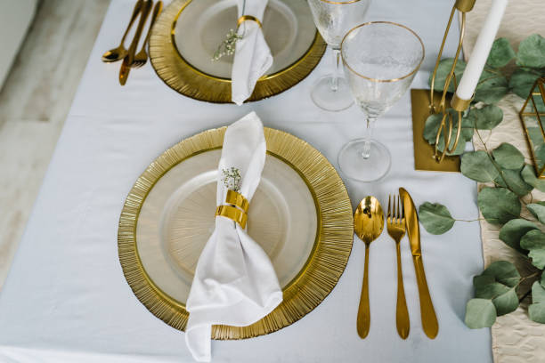 istock Festive table setting with plate, golden cutlery set and eucalyptus leaves, candles. Dinner table decorated for cozy fall holiday gathering in kitchen. Top view. Element for design. Spring table setup 1490665120