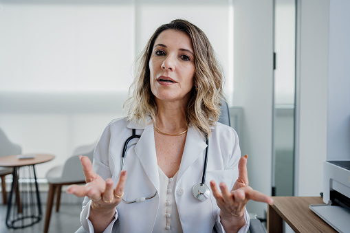 Retrato de una doctora hablando a la cámara en la atención en línea photo