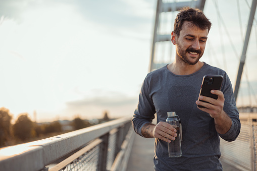 Athlete runner with bottle and smartphone for Fitness App