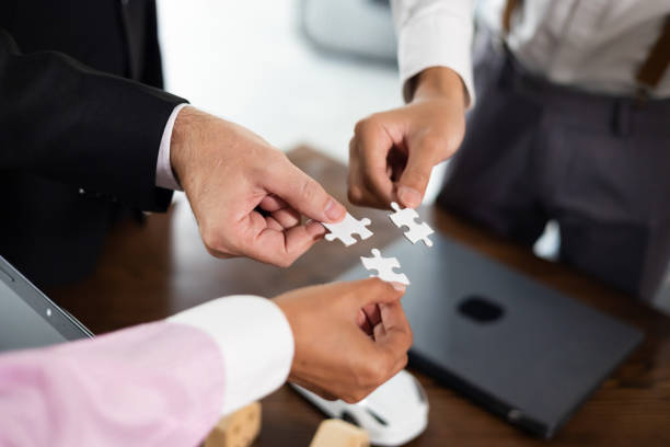 istock Group of diverse business people assembling jigsaw puzzle. Unity and teamwork concept 1490667347