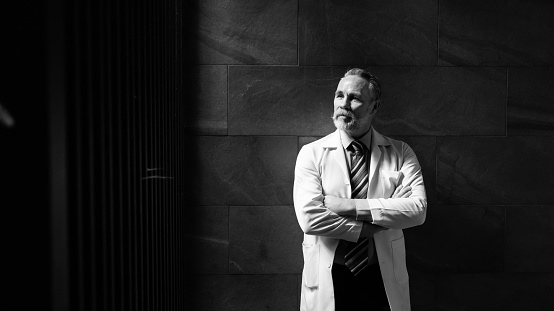 Hight contrast and drama concept. Portrait caucasian senior man doctor posing and standing at wellness center and hospital. healthcare and medicine