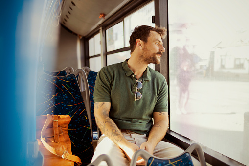Man looking through window while traveling in bus