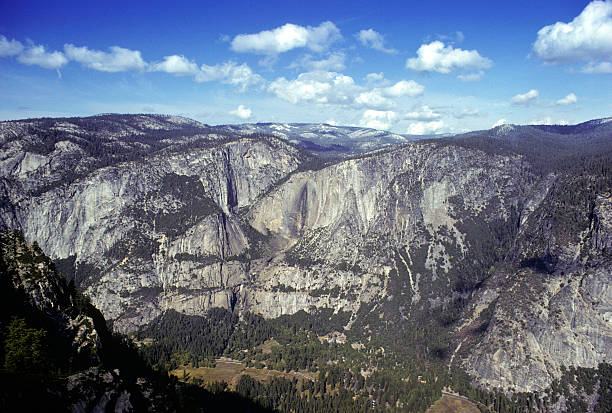 Yosemite Valley, summer, circa 1978 A "side" view of Yosemite valley, with the lodge hiding in the trees below. Daytime, with clouds, and you can see that it's summertime because the waterfalls are trickles. hearkencreative stock pictures, royalty-free photos & images