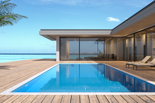 3D render of a single-storey, luxury villa in modern and minimalist architecture.\nThe villa's floor-to-ceiling windows provide an uninterrupted view of the stunning tropical ocean backdrop.\nThe villa's private backyard features a swimming pool set within a wooden deck, complete with two loungers for relaxation.