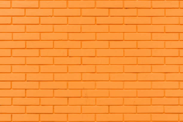 Vibrant orange brick wall pattern as graphic design element and background. Texture of a house exterior surface.