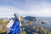 Young woman on mountain top looks at the spectacular scenery, Norway