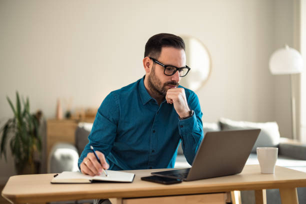 istock Man working over the laptop and taking notes in a notebook, sitting at the office. 1490674098