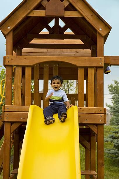 Excited Toddler Sitting in a Tree-House Ready to Slide stock photo