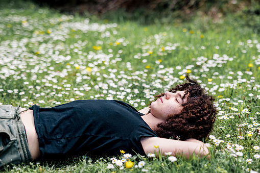 Teenage boy lying down on grass at springtime
