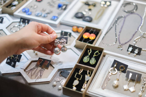 istock beautifully crafted earring is being chosen by a woman's hand, with a diverse selection of handmade bijouterie adorning the stall behind. art of creating handmade jewelry, traditional craftsmanship 1490675997