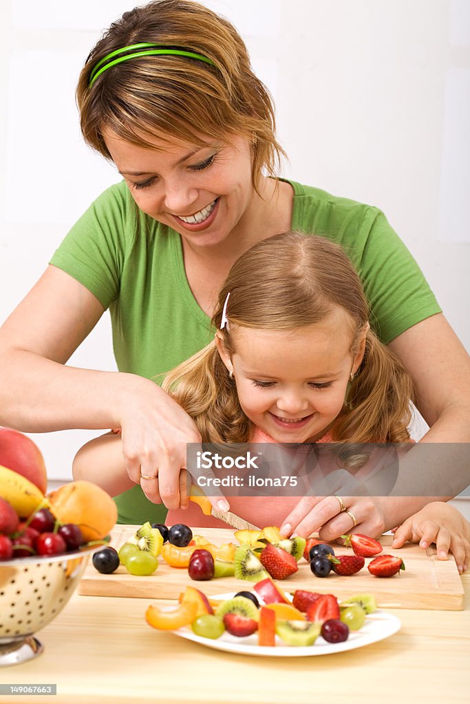 Making fruit salad is healthy and fun Little girl and her mom having fun preparing summer fruits salad Child Stock Photo
