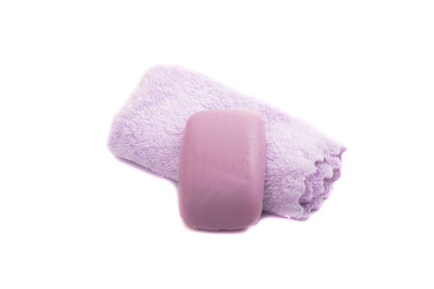 Soap, washcloth and terry towels on white background.