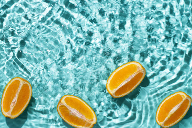 istock Creative summer background with orange fruit slices in swimming pool water. 1490677440