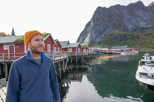 He looks around the beautiful scenery on a sunny day.\nLofoten islands, Norway\nHouses with roofs covered with grass, sustainable energy