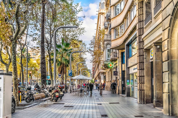 Barcelona, Spain - November 26, 2021: Autumn cityscape in Barcelona on Avinguda Diagonal. People walk along the pedestrian sidewalk among the ancient historical buildings and trees with golden foliage