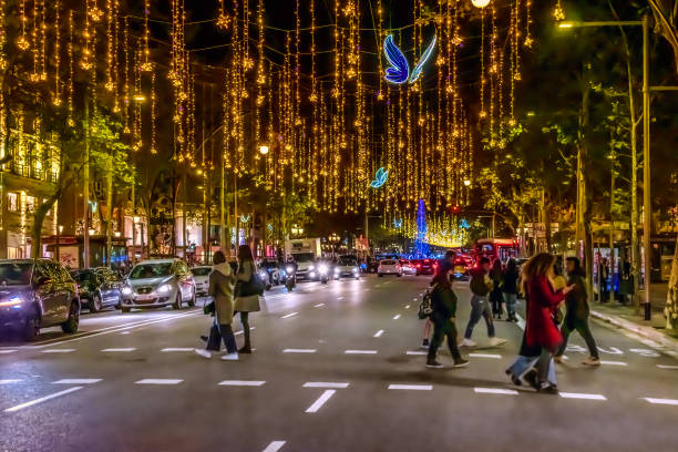 blau leuchtende schmetterlinge und goldene girlanden hängen nachts über der straße auf dem passeig de gracia in barcelona - passeig de gracia stock-fotos und bilder