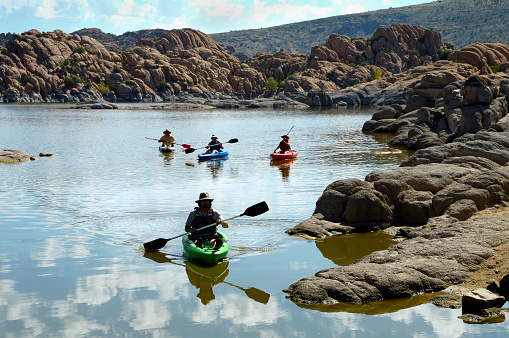 Arizona, USA. 08/23/2018.  Group of adventurous friends canoeing in colorful canoes in tranquil Watson Lake, Arizona, USA on a warm, sunny morning.