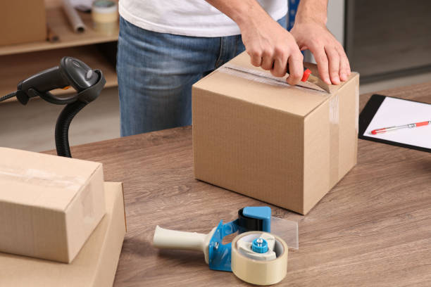 istock Post office worker with utility knife opening parcel at counter indoors, closeup 1490683189