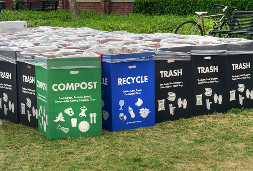 large number of cardboard boxes lined with plastic garbage bags, labeled for for compost, recycling, and trash, set out on campus at USC on graduation day, Los Angeles, CA