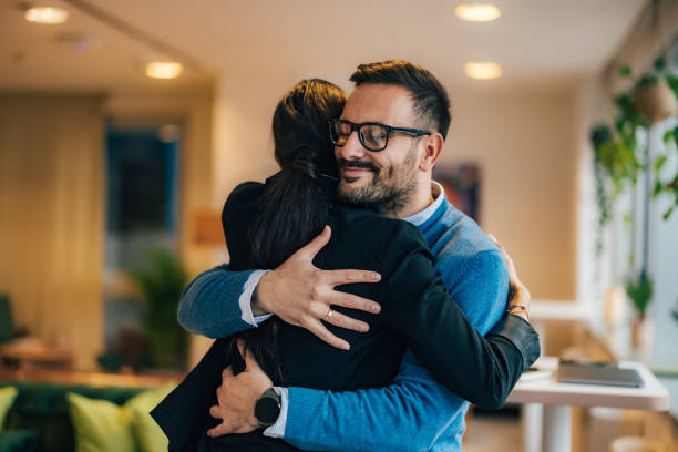 Smiling business colleagues hugging each other at the office.