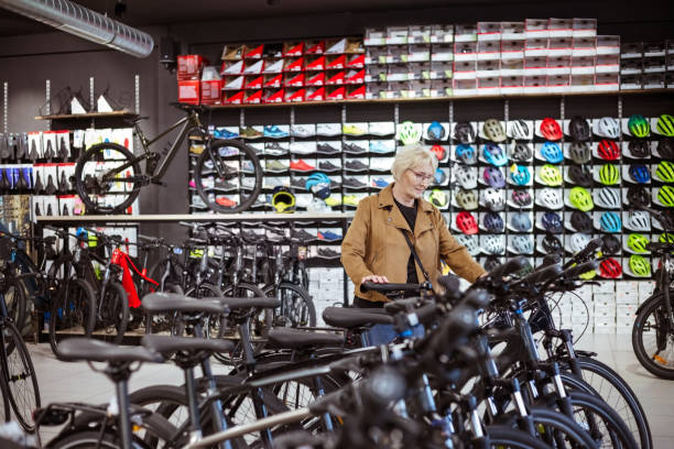 Senior woman watching bicycle in bike shop.