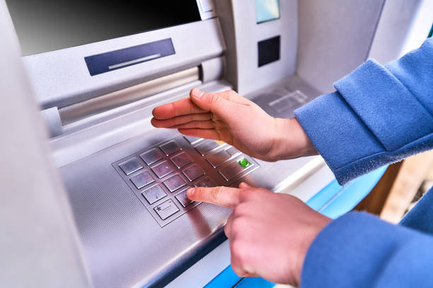 istock Person dials and hides with other hand for security purposes a PIN code on the keyboard of atm bank to withdraw cash 1490697822