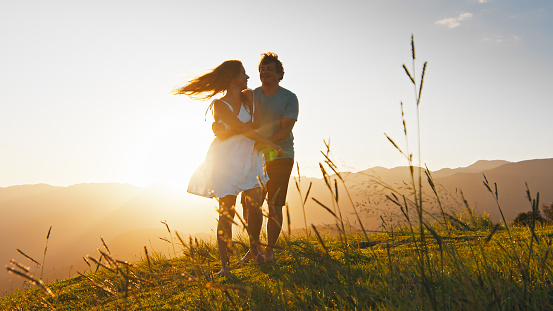 Man and woman dance on the summer meadow with grass at sunrise