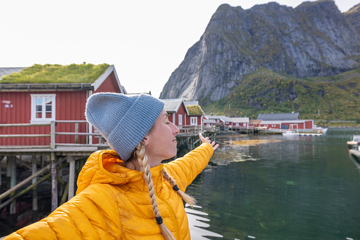 She enjoys the fresh air arm stretches her arms wide open \nLofoten islands, Norway\nHouses with roofs covered with grass, sustainable energy