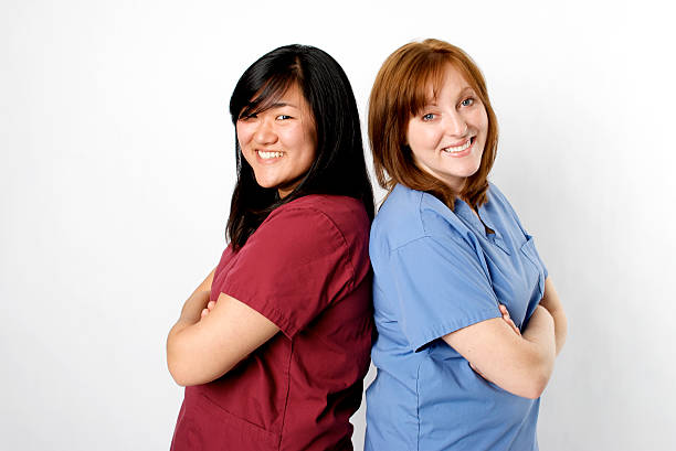 Confident Nurses Two Confident Nurses Back to Back on a white background red medical scrubs stock pictures, royalty-free photos & images