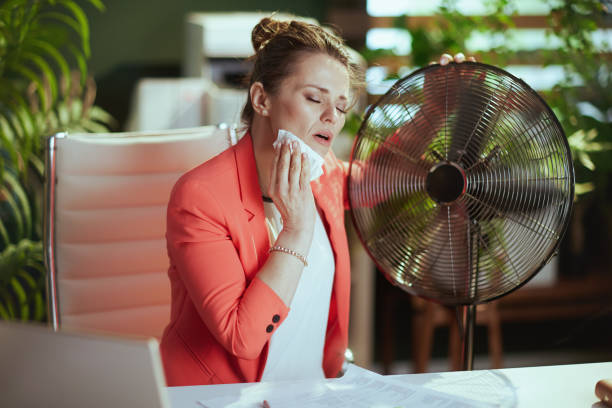 mujer tenedora de libros de 40 años en oficina verde sufre de calor - menopausia fotografías e imágenes de stock
