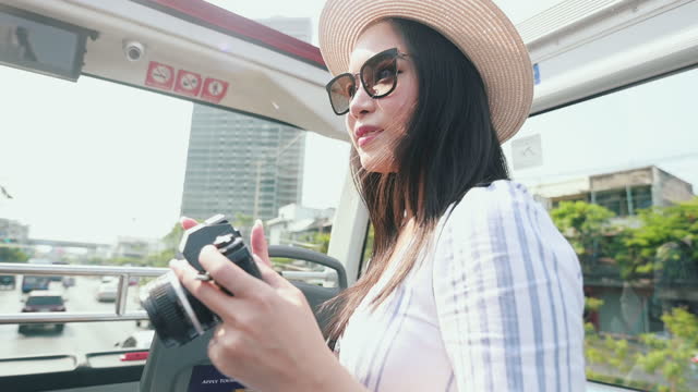 Cute Asian woman on the tourist bus with film camera