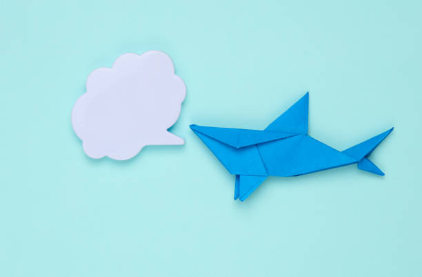 Origami paper shark with speech bubble on blue background