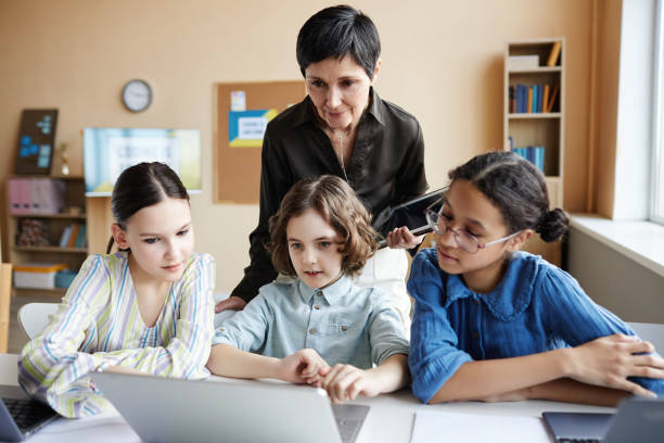 istock Teacher helping children with online presentation 1490709075